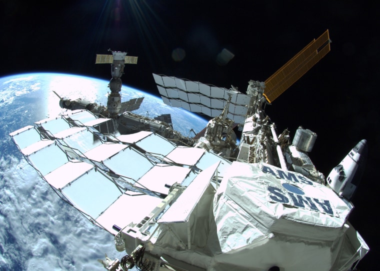 A fish-eye view of the International Space Station, captured by Ron Garan last July, features the Alpha Magnetic Spectrometer in the foreground. A Russian Progress cargo ship and a Soyuz crew capsule are docked on the left end of the station. The structure extending to the left of the AMS is a thermal radiator. One of the station's gold-colored solar arrays is visible in the background. And off to the right, the shuttle Atlantis is docked to the station's Tranquility module.