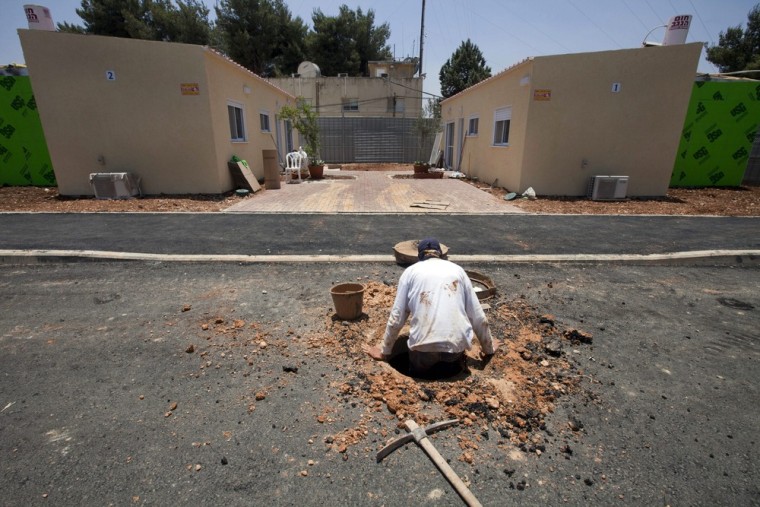 A Palestinian worker emerges from a sewer pipe near two Jewish settler homes in a new neighborhood being established on the outskirts of the Beit El settlement.