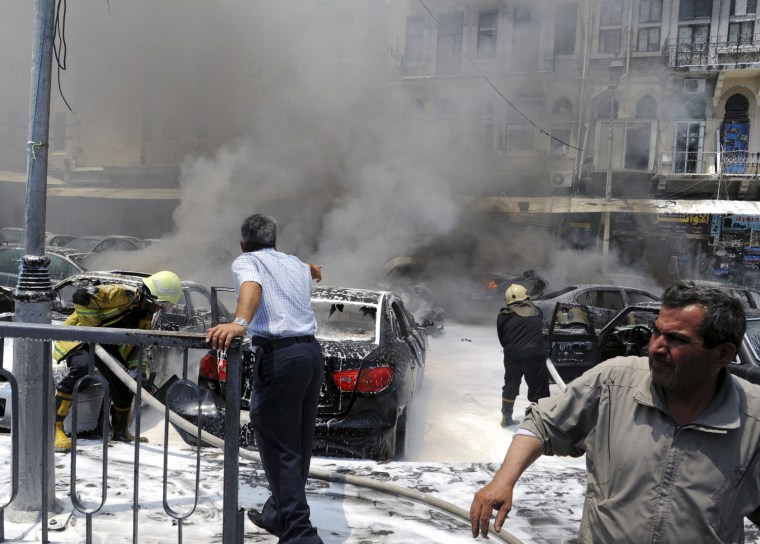 Civil Defence members extinguish fires on cars at the site of an explosion outside Syria's highest court in central Damascus on June 28, 2012.