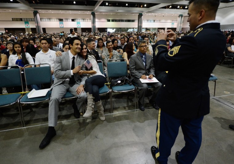 Gilles Marini, left, poses with the wife of his friend Regina Deleo as they get a picture taken by US Army Ssg. Fabrizio Bustos before Marini and Bustos took the oath of citizenship.