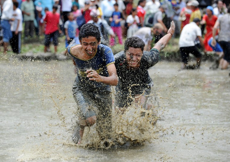 Nepalese youth play in the mud as they plant rice in a field in Pokhara, west of Kathmandu on June 29. The farmers are celebrating National Paddy Day on 'Asar 15' of the Nepali calendar as the annual rice planting season begins.
