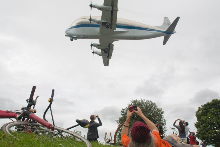 A crowd in the Georgetown neighborhood of Seattle watches NASA's Super Guppy aircraft approach the King County International Airport in Washington. The airplane is carrying a Space Shuttle Trainer headed for the Museum of Flight in Seattle.