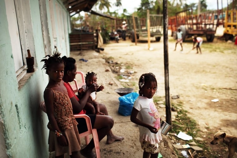 SAN PEDRO, DOMINICAN REPUBLIC - MARCH 01: A Haitian family stands near their home on a sugar cane batey on March 01, 2012 in San Pedro, Dominican Republic. A batey is the name given to communities that reside inside of sugar plantations in the Dominican Republic that are comprised mainly of Haitians and Dominicans of Haitian descent. Living and working conditions inside the bateyes are often extremely impoverished, with limited access to health care, no running water or sanitary facilities and a lack of electricity. For decades Haitians have been fleeing the turmoil of their country to come and work as seasonal workers in the sugar cane industry in the Dominican Republic, with many staying on permanently in the country. It is estimated that somewhere between 500,000 and 1,000,000 Haitians are currently living Dominican Republic. Due to a climate of discrimination based on ethnic origins and a fear of a Haitian influx, the Dominican government has adopted policies that make it difficult to impossible for many Haitians to live a normal life in the country. (Photo by Spencer Platt/Getty Images)