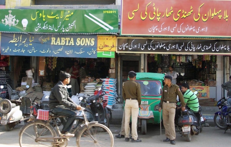 Indian police stand outside shops adorned with temporary signs written in Urdu, Pakistan's official language, to be filmed for scenes depicting Pakistan's Abbottabad town.