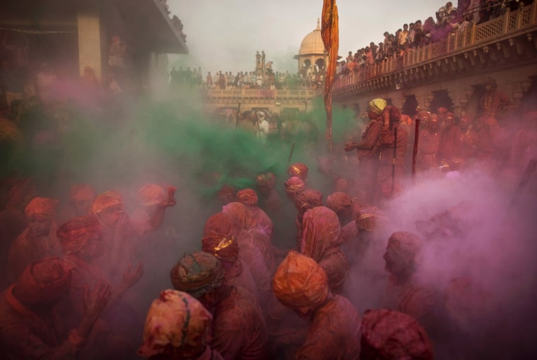 Indian Hindu worshippers pray as others throw colored powder and water on them during Lathmar Holi at Nandagram Temple, in Nandgaon,India, Saturday, March 3, 2012. According to tradition which has its roots in Hindu mythology men from Barsana arrive at the temple where they are soaked in colored water by men from Nandgaon, believed to be Lord Krishna's village, and then beaten by the women of the village with wooden sticks as they depart the town. (AP Photo/Kevin Frayer)