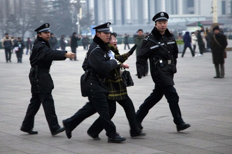A Chinese police officer drags away a protesting woman after a flag raising ceremony on Tiananmen Square across from where the National People's Congress is held, in Beijing, China, Monday, March 5, 2012. The cause of the incident was not known but authorities have tighten security of the area around the Great Hall of the People where the annual legislature meetings are held this week. (AP Photo/Andy Wong)