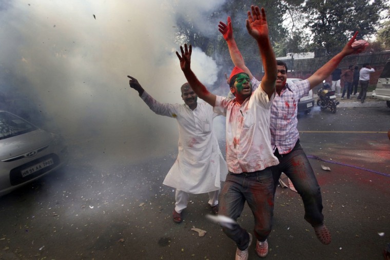 Samajwadi Party supporters, faces smeared with colored powder, celebrate by burning firecrackers at their party office in New Delhi, India, Tuesday, March 6, 2012. Election officials across five Indian states Tuesday began counting votes in crucial provincial elections that are being seen as a test of strength for the country's ruling Congress party. (AP Photo/ Manish Swarup)