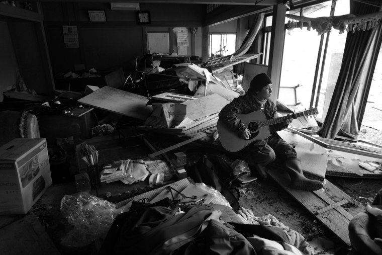 Masanori Sato plays a guitar in his debri-filled-house in MInamisanriku, Miyagi, Japan on March 31, 2011 following a massive earthquake and tsunami that hit northern Japan on March 11. Photo by Kuni Takahashi