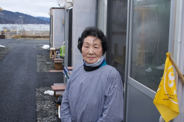 Junko Takashi, 79, stands outside her temporary home in the tsunami-devastated town of Otsuchi, Japan. All of the town's residents over 65 have a yellow flag they put out in the morning and take down in the evening. If no flag appears in the morning, then officials come and check on them.