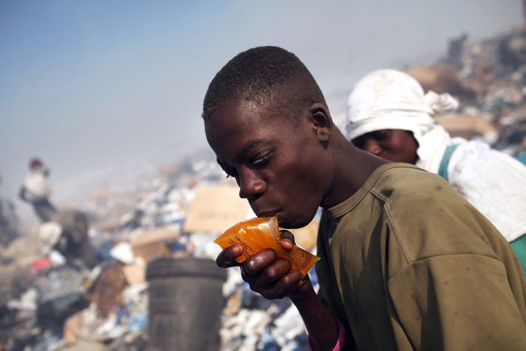 PORT-AU-PRINCE, HAITI - MARCH 07: A boy takes a drink as he scavenges for recyclable and other usable items at the Trutier dump on the outskirts of Port-au-Prince, on March 7, 2012 in Port-au-Prince, Haiti. Following the devastating earthquake two years ago that killed and estimated 316,000 people, the number of scavengers at the landfill has grown from about 200 to an estimated 2,000. Much of Haiti is still in a crisis situation with tens of thousands living in tent camps in and around Port-au-Prince. A growing concern to international donors is a flare-up between ex-members of Haiti's armed forces and the current Haitian President Michel Martelly. (Photo by Spencer Platt/Getty Images)