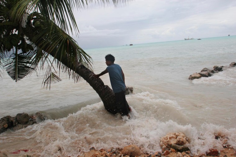 In this photo released by Greenpeace, Pita Meanke, of Betio village, stands beside a tree as he watches the 'king tides' crash through the sea wall his family built onto his family property, on the South Pacific island of Kiribati, Thursday, Feb. 10, 2005. (AP Photo/Greenpeace, Jeremy Sutton-Hibbert) ** NO ARCHIVES NO SALES **