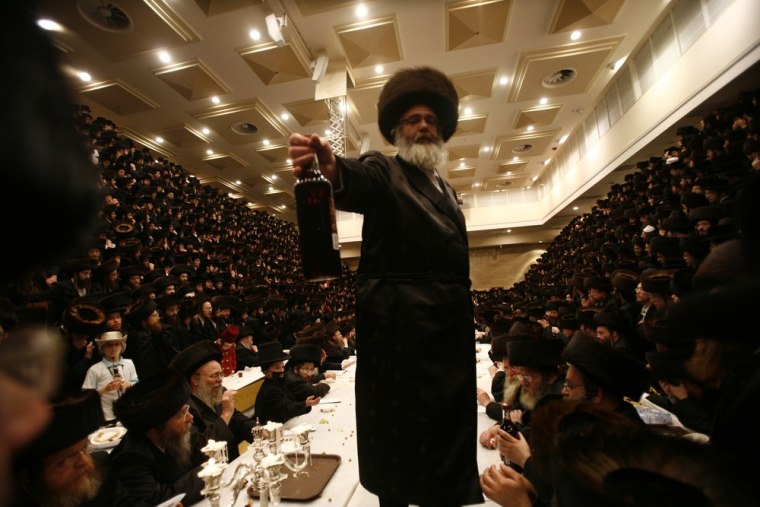 An Ultra-Orthodox Jewish man hands out a bottle of wine during celebrations for the holiday of Purim at the Belz Hasidic dynasty synagogue in Jerusalem March 8, 2012. Purim is a celebration of the Jews' salvation from genocide in ancient Persia, as recounted in the Book of Esther. REUTERS/Baz Ratner (JERUSALEM - Tags: RELIGION SOCIETY)