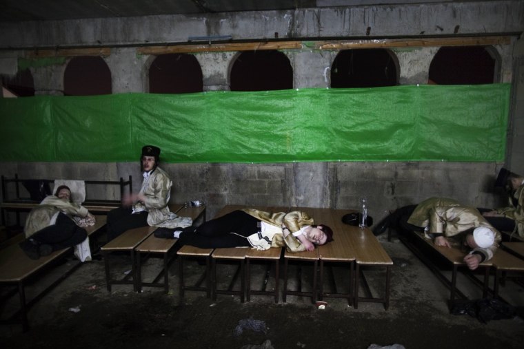 Ultra-Orthodox Jews belonging to the Tholdot Avraham Yitzhak Hasidic sit and lay during the Jewish festival of Purim late on March 8, 2012 in Beit Shemesh, a religious town near Jerusalem. Purim marks the deliverance of the Jewish people from a genocidal plot in ancient Persia, as recorded in the Biblical Book of Esther. AFP PHOTO/MENAHEM KAHANA (Photo credit should read MENAHEM KAHANA/AFP/Getty Images)
