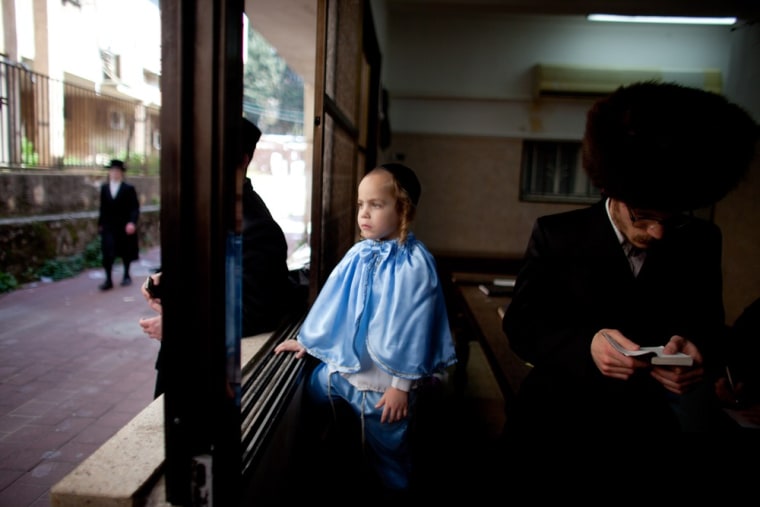 BENEI, BRAK ISRAEL - MARCH 08: A boy looks out of a window as Ultra Orthodox Jews celebrate the Jewish holiday of Purim on March 8, 2012 in Benei Brak, Israel. The carnival-like Purim holiday is celebrated with parades and costume parties to commemorate the deliverance of the Jewish people from a plot to exterminate them in the ancient Persian empire 2,500 years ago, as described in the Book of Esther. (Photo by Uriel Sinai/Getty Images)