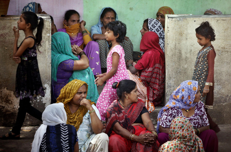 Relatives of 13-year old Viky Walmiki, who died from poisoning from colored powder and water used during Holi celebrations, gather outside his house in Mumbai, India, Friday, March 9, 2012. More than 140 children from Dharavi area of Mumbai were hospitalized following use of toxic colors, according to a news agency. (AP Photo/Rajanish Kakade)