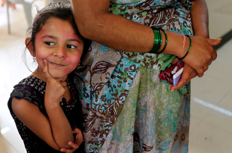 5-year-old Ritika Borde, a victim of poisoning from colored powder and water used during Holi celebrations, stands in a queue to be treated at a government hospital in Mumbai, India, Friday, March 9, 2012. More than 140 children from Dharavi area of Mumbai were hospitalized following use of toxic colors, according to a news agency. (AP Photo/Rajanish Kakade)