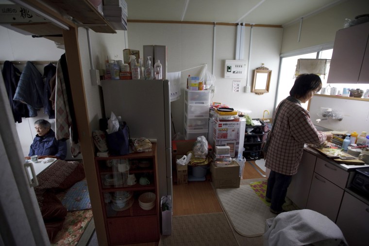Katsushi Haga, 67, sits in his temporary house as his wife, Eiko, 61, cooks at the kitchen in Koizumi district of Kesennuma in Miyagi prefecture, Japan on Feb 27, 2012. The tsunami on March 11, 2011 flattened the district, destroying 266 of its 518 households and killed about 30 of its estimated 1,800 residents, including Haga’s 87-year-old mother, Tomiko. Photo by Kuni Takahashi