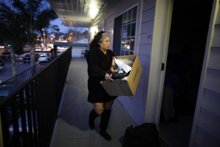 Benita takes her belongings into a motel room in Port Hueneme. After three weeks of sleeping at a campsite, the family could no longer afford a rental van to ferry the kids to school and had to find a cheap motel room for the night, so the children could walk to school.