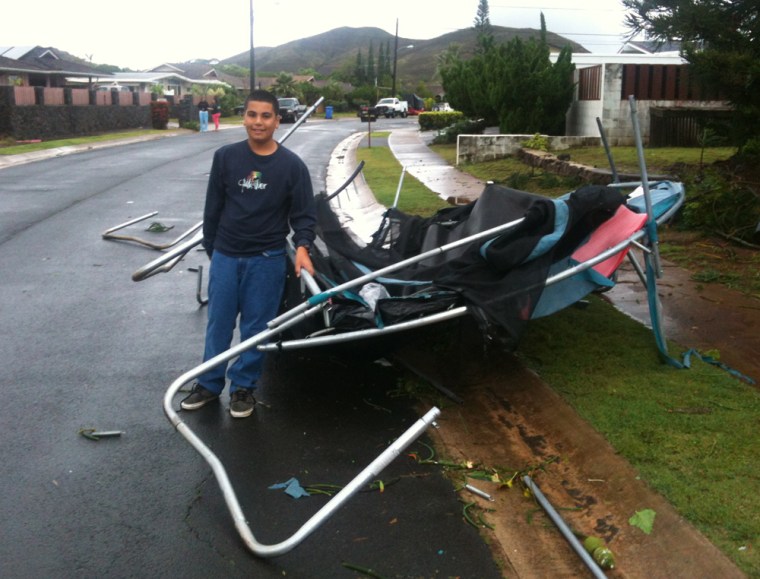 2012 March 09 CTY - Kahili street enchanted lake. Kaeo DePonte stands with the trampoline that was lifted out of the yard of the house across the street at left --- leaving the fence intact.
