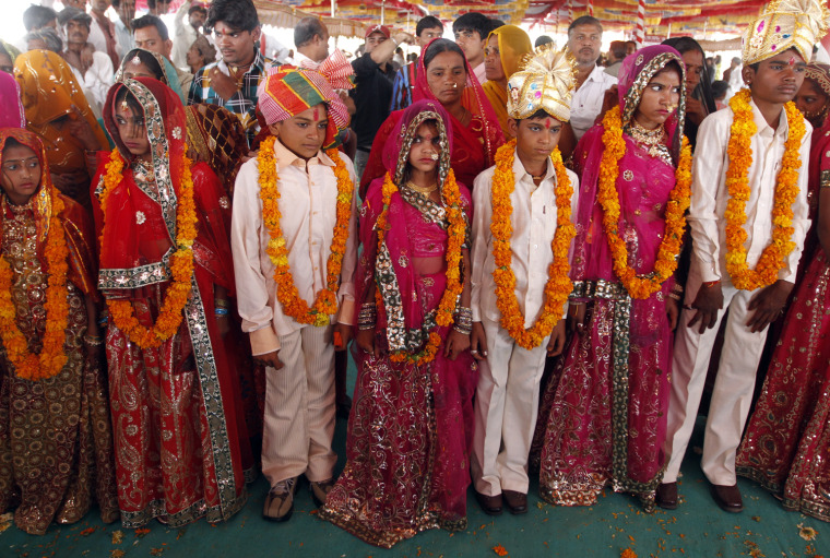 Boys and girls from the Saraniya community wearing garlands pose for pictures after their engagement ceremony at Vadia village in the western Indian state of Gujarat March 11, 2012. The Vadia village in western India hosted a mass wedding and engagement ceremony of 21 girls on Sunday aimed at breaking a tradition of prostitution which has for centuries exploited women of a poor, marginalised and once nomadic community in the region. REUTERS/Amit Dave (INDIA - Tags: SOCIETY)