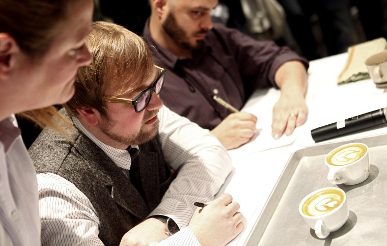 Judges evaluate lattes in a number of different categories such as aesthetic beauty and color infusion, among others, in the Coffee Fest New York Latte Art Championships at the Javits Center in New York March 11, 2012. REUTERS/Carlo Allegri (UNITED STATES - Tags: SOCIETY)