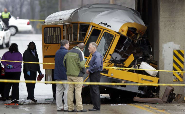 Investigators look over the scene of a fatal bus crash on the southeast side of Indianapolis, Monday, March 12, 2012. The driver and one student were killed and two other critically injured. (AP Photo/Michael Conroy)