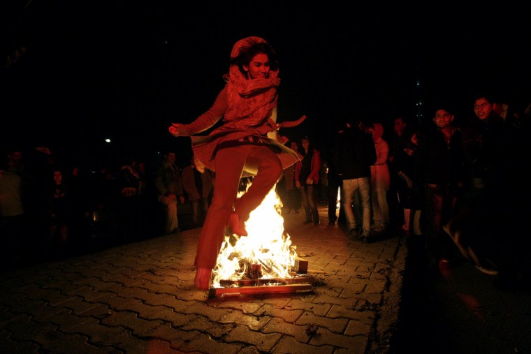 An Iranian woman jumps over a bonfire, in the Pardisan Park in Tehran, Iran, Tuesday, March 13, 2012, during Chaharshanbe Souri, or Wednesday Feast, an ancient Festival of Fire, on the eve of the last Wednesday of the year. Iranians jump over burning bonfires while throwing firecrackers, celebrate arrival of the spring which coincides with Iranian new year, or Nowruz. Setting off firecrackers has turned into careless massive explosions in the recent years, which leaves many wounded every year, prompting strong reactions by police. The festival, came from pre-Islamic Zoroastrianism era, has been discouraged by conservative Islamist rulers after 1979 Islamic Revolution, but without any success. (AP Photo/Vahid Salemi)