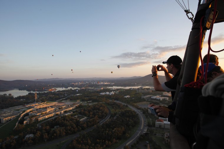 epa03143660 A passenger takes pictures of Parliament House from a hot air balloon in Canberra, Australia, 14 March 2012. The Balloon Spectacular is one of the major events of the Canberra Festival and is listed as one of the top four hot ballooning events in the world. EPA/LUKAS COCH AUSTRALIA AND NEW ZEALAND OUT