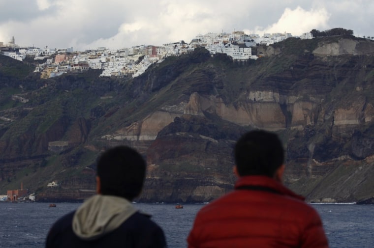 Foreign tourists admire the volcanic island of Santorini.