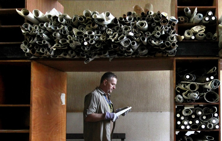 In this Tuesday March 13, 2012 Brett Irwin of the Public Record Office moves old plans of Harland and Wolff ships from the 19th century in the Titanic Drawing Offices, situated close to the new £100 million Titanic Belfast Vistor Centre, Belfast, Northern Ireland. The plans for Titanic and sister ship Olympic were devised by Harland&Wolff in this building. Celebrating the ship and the people who built her is the aim of Titanic Belfast, a shiny new