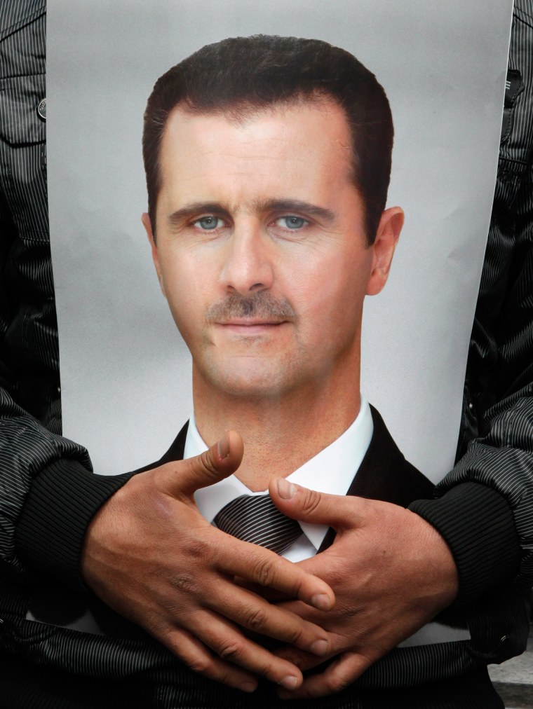 A man puts a picture of Syria's President Bashar al-Assad on his chest as he attends a rally at Umayyad square in Damascus March 15, 2012. Several government rallies took place across the country for support of Assad. REUTERS/Khaled al-Hariri (SYRIA - Tags: POLITICS CIVIL UNREST)