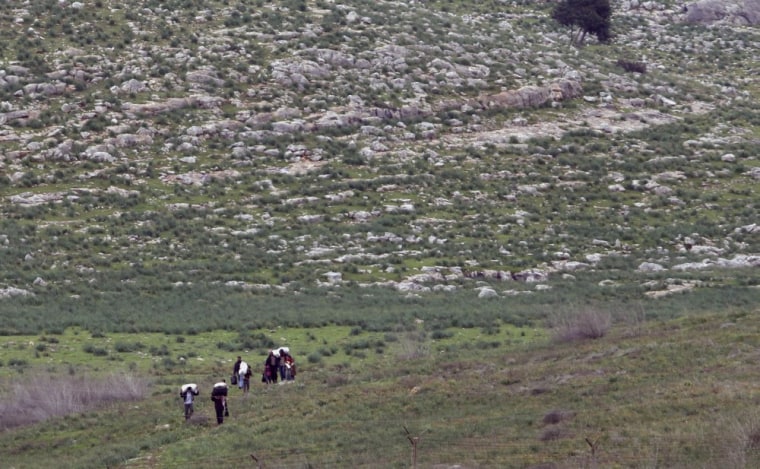 A group of Syrian fleeing violence in their country, walk towards the Turkish, near Reyhanli, Turkey, Thursday, March 15, 2012. An official says more than 1,000 Syrians have crossed into Turkey over the past 24 hours, bringing the total number of Syrian refugees in Turkey to at least 14,700. (AP Photo/Burhan Ozbilici)