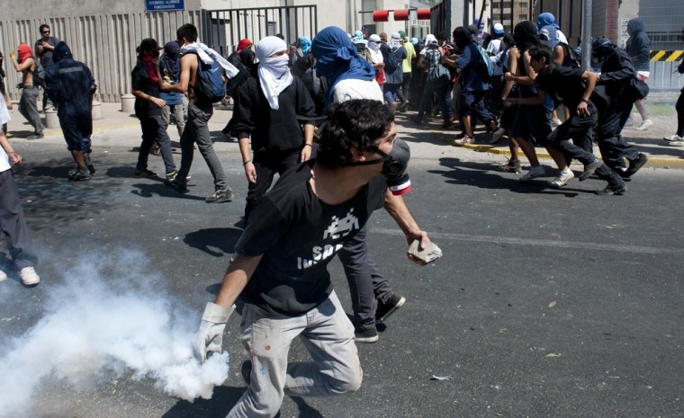 A Chilean student throws back a tear gas canister at riot police during a protest against the government of President Sebastian Pinera, in Santiago on March 15 ,2012. AFP PHOTO MARTIN BERNETTI (Photo credit should read MARTIN BERNETTI/AFP/Getty Images)