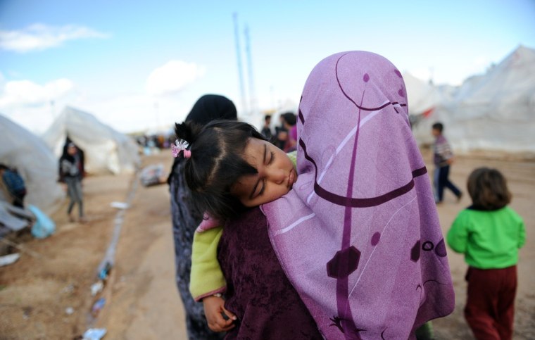 A girl carries tomatoes as Syrian refugees go about their daily lives at the Reyhanli refugee Camp in Antakya, on March 15, 2012. Around 1,000 Syrian refugees, including a defecting general, crossed into Turkey in the last 24 hours, the foreign ministry said on Thursday, the one-year anniversary of the Syrian revolt. Ankara accused the Syrian leadership of planting landmines near its border with Turkey along routes used by refugees fleeing the Damascus regime's deadly crackdown on dissent. AFP PHOTO / BULENT KILIC (Photo credit should read BULENT KILIC/AFP/Getty Images)