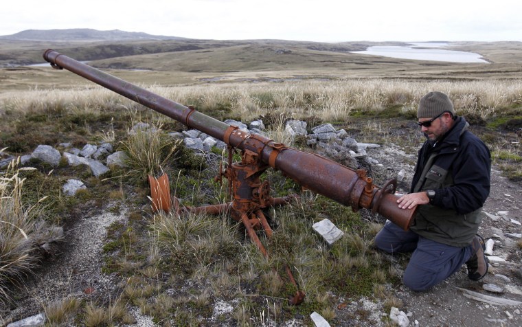 Argentine Falklands War veteran Marcelo Postonia kneels down next to the cannon he used during the conflict near Port Stanley.