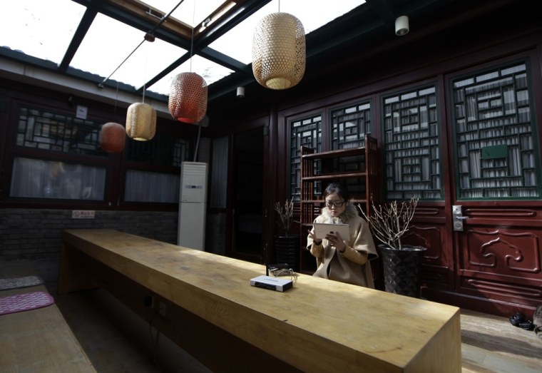 Ms. Zhuang, a Hotel Test Sleeper, checks the network speed of wifi on her iPad at the public area of a Beijing traditional hotel with courtyard houses, known as