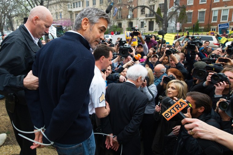 Actor and activist George Clooney (2nd L) and his father journalist Nick Clooney (C) are arrested for trespassing upon the Sudanese Embassy in Washington, DC, on March 16, 2012. Clooney and his father were protesting against human rights abuses by the Sudanese government. AFP PHOTO/PAUL J. RICHARDS (Photo credit should read PAUL J. RICHARDS/AFP/Getty Images)