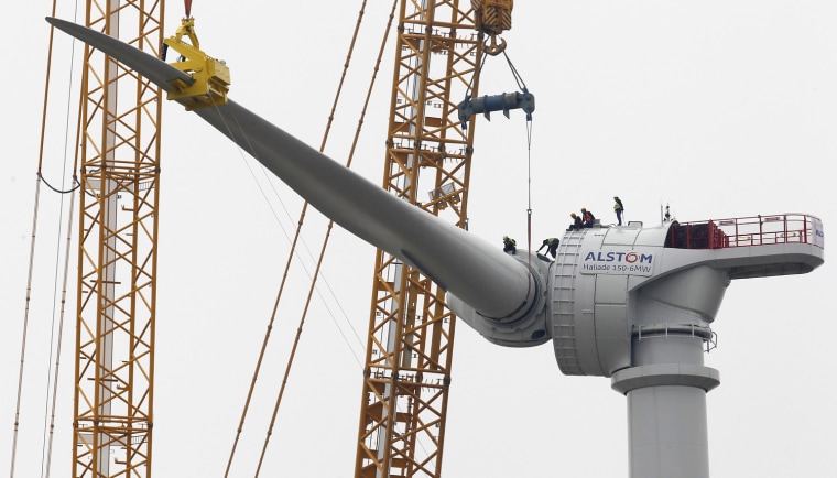 Technicians install a wind turbine blade at Alstom's offshore wind site in Le Carnet, on the Loire Estuary, near Saint Nazaire, March 16, 2012. French power and transport engineering company Alstom will start its new direct drive Haliade 150 - 6MW offshore wind turbine in April.