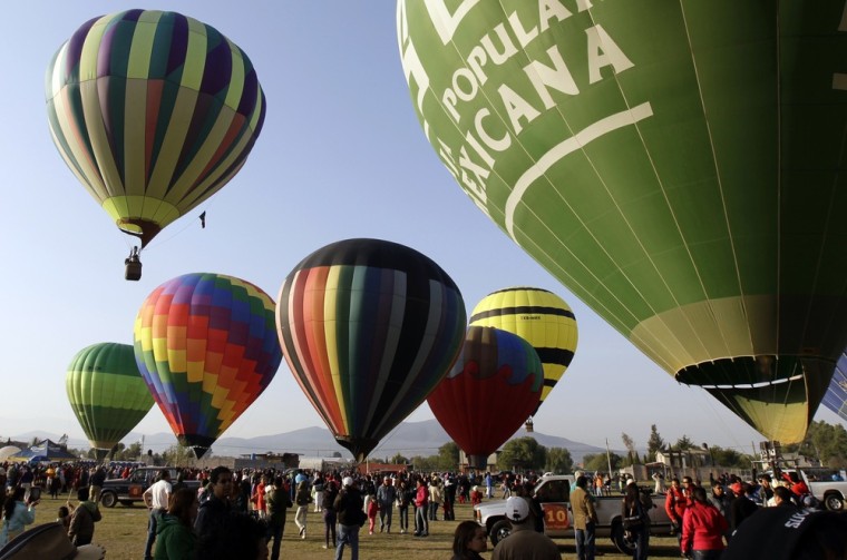 People watch as hot air balloons float near the Pyramids of Teotihuacan during the international hot air balloon festival outside Mexico City.