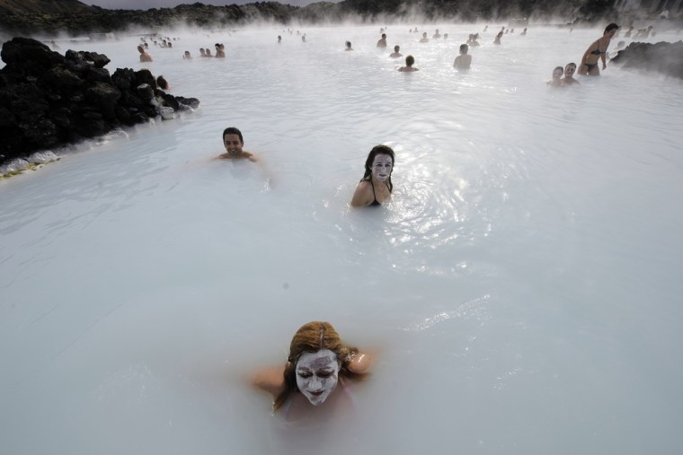 TOPSHOTSTourists stand in the Blue Lagoon outside Reykjavik on 26 April, 2009. The Blue Lagoon's blue and green waters come from natural hot water springs flowing through rocks of lava. The  lagoon might have some health properties. AFP PHOTO OLIVIER MORIN. (Photo credit should read OLIVIER MORIN/AFP/Getty Images)