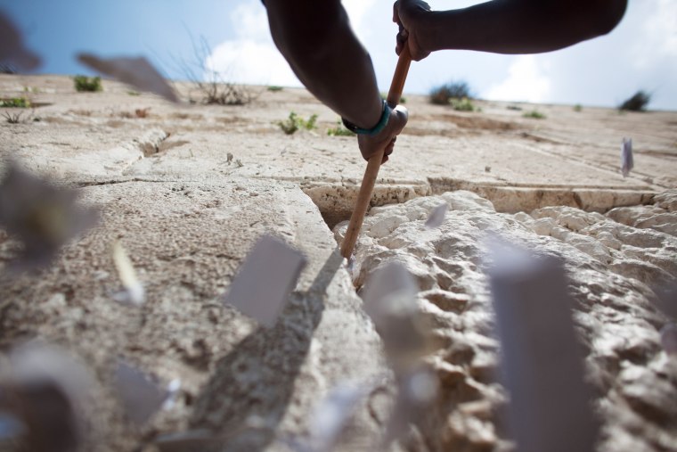 JERUSALEM, ISRAEL - MARCH 28: (ISRAEL OUT) A man helps remove messages and prayers written by thousands of people addressed to God from the cracks in the Western Wall in preparation for the up coming Jewish Passover holiday on March 28, 2012 in Jerusalem's old city, Israel. All the notes once collected will be buried in a special place at the Mount of Olives.according tro Jewish law. Passover begins in the evening of Friday, April 6 and commemorates the story of the Exodus where the ancient Israelites were freed from slavery in Egypt. (Photo by Uriel Sinai/Getty Images)