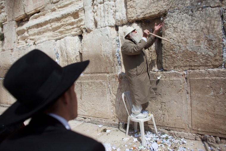 JERUSALEM, ISRAEL - MARCH 28: (ISRAEL OUT) A man helps remove messages and prayers written by thousands of people addressed to God from the cracks in the Western Wall in preparation for the up coming Jewish Passover holiday on March 28, 2012 in Jerusalem's old city, Israel. All the notes once collected will be buried in a special place at the Mount of Olives.according tro Jewish law. Passover begins in the evening of Friday, April 6 and commemorates the story of the Exodus where the ancient Israelites were freed from slavery in Egypt. (Photo by Uriel Sinai/Getty Images)