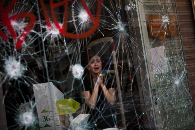 Mirian Burrueco, 30, reacts behind the broken glass of her shop stormed by demonstrators during clashes at the general strike in Barcelona on March 29.
