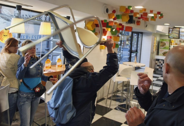 A protester throws a chair inside a food shop in Madrid on March 29 during a general strike.