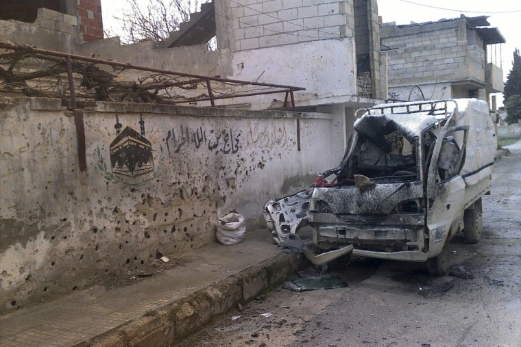 A damaged vehicle is seen next to a damaged building in Al Qasseer city, near Homs, Syria, March 28.