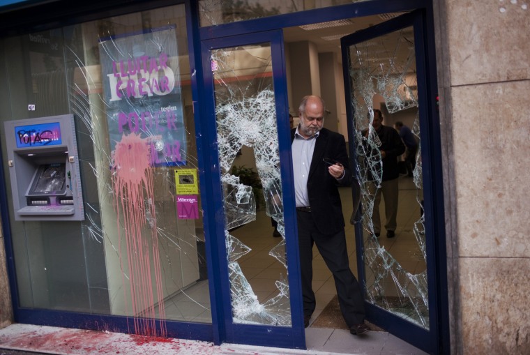 A man leaves a bank stormed by demonstrators following clashes between police and protesters after a general strike in Barcelona, Spain, on March 30. The Spanish government prepared to approve on Friday a new austerity budget that hundreds of thousands protested against this week in sometimes violent demonstrations.