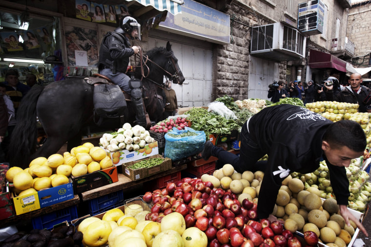 A Palestinian youth climbs over a fruit stall as an Israeli mounted policeman disperses hundreds of Palestinian protesters during a demonstration marking Land Day in east Jerusalem on March 30. Demonstrators waving huge Palestinian flags gathered for Land Day, sparking scuffles with hundreds of Israeli police who were seen beating some of the crowd, an AFP correspondent said.