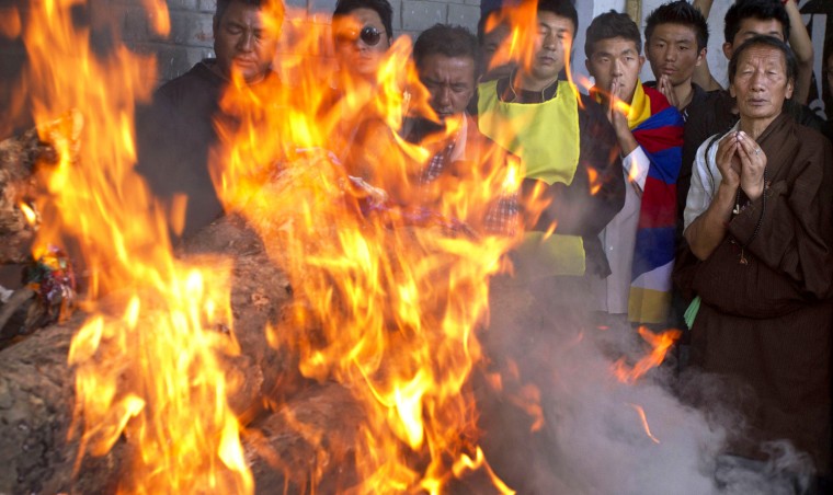 Tibetan exiles pray next to the burning funeral pyre of 27-year-old Jamphel Yeshi, who passed away Wednesday morning two days after he immolated himself in New Delhi.