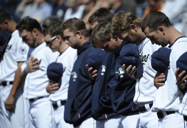 San Diego Padres players bow their heads in a moment of silence for San Diego Chargers player Junior Seau before a baseball game against the Milwaukee Brewers Petco Park in San Diego.