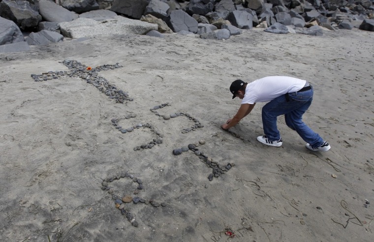 Jimmy Garcia constructs a make-shift memorial on the beach near the home of former NFL star Junior Seau in Oceanside.